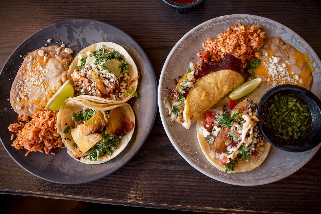 Two plates of tacos, rice, and beans at Merry Piglets Mexican Grill