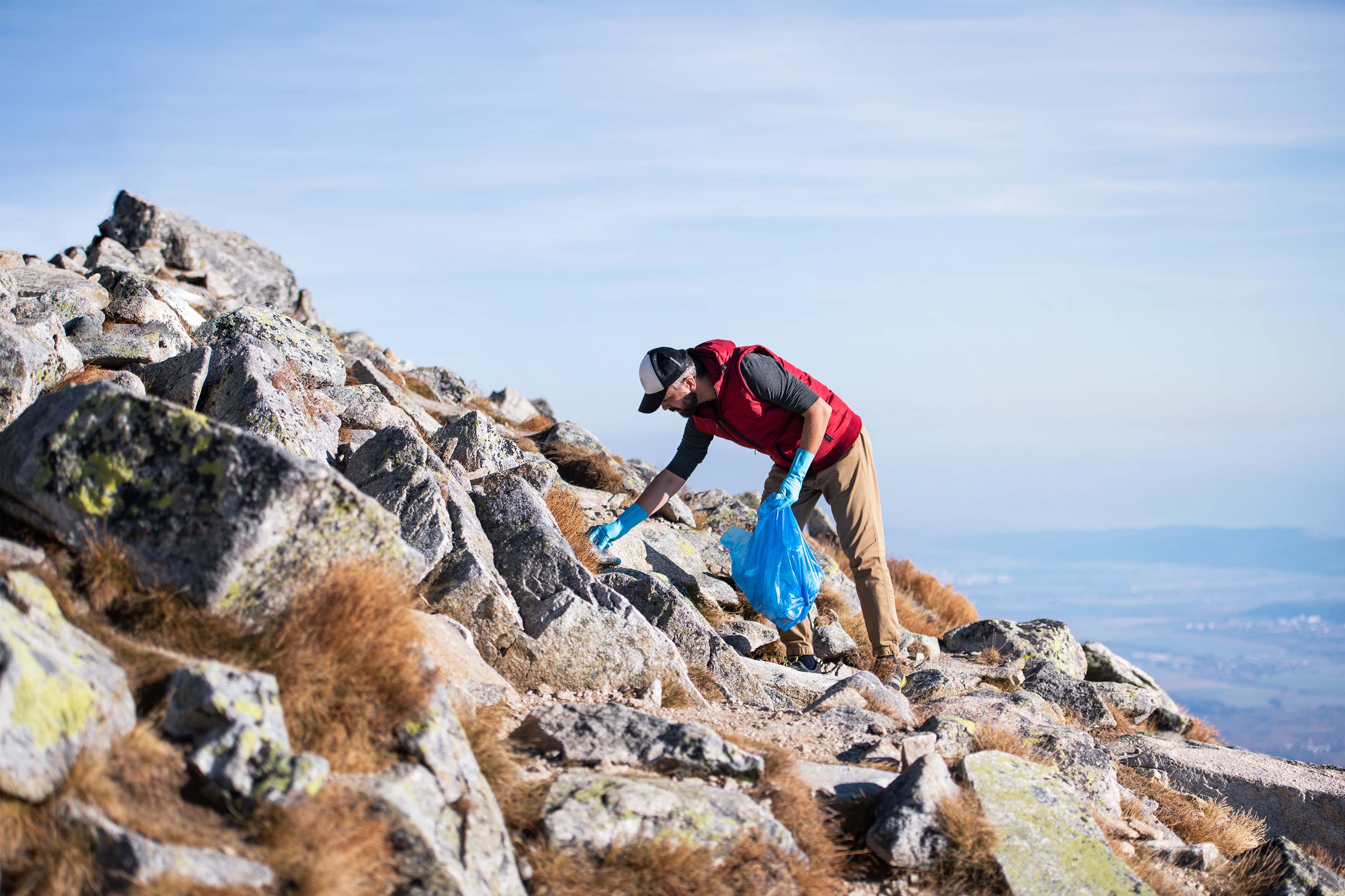man picking up trash in the mountains