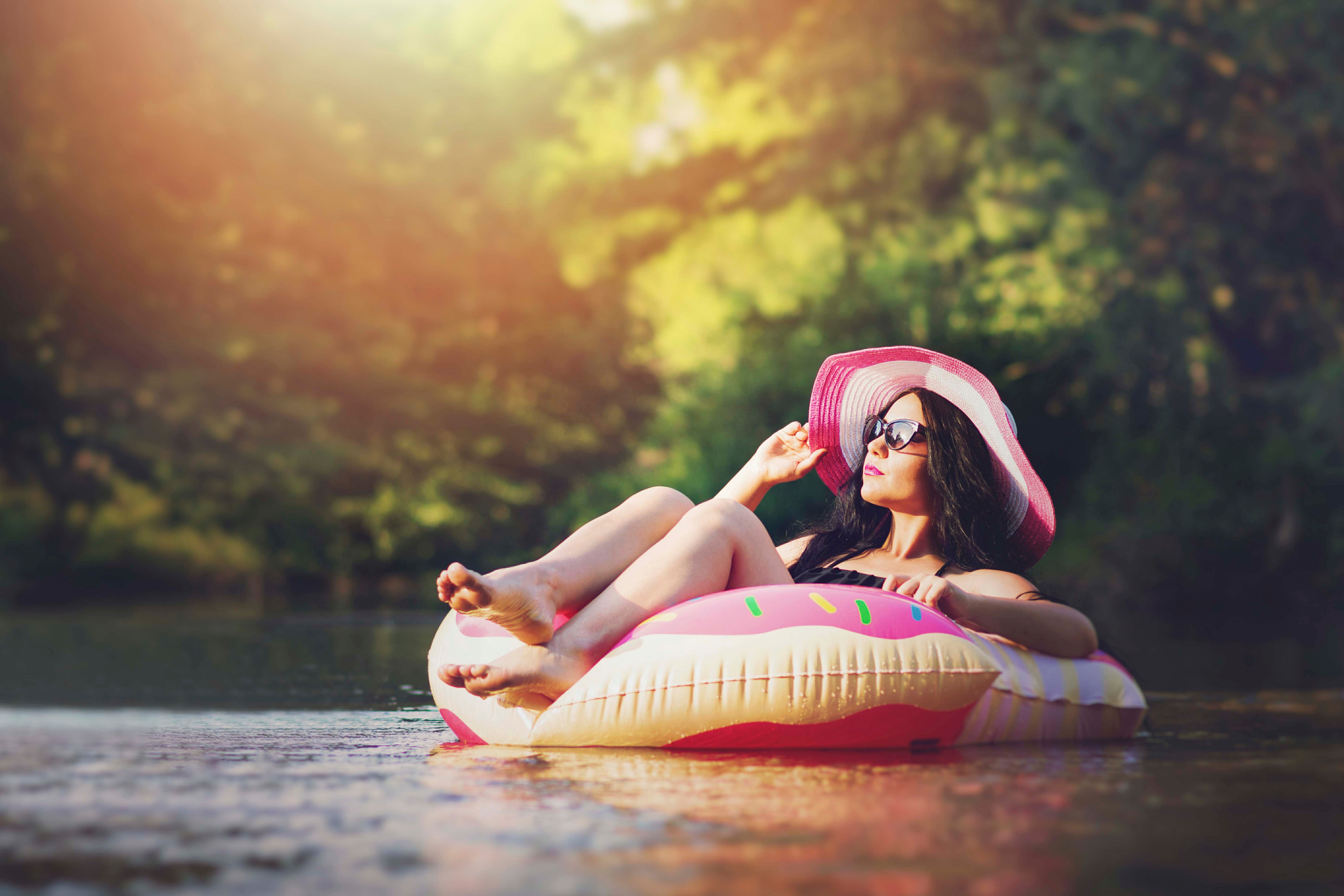 woman floating on a river while wearing a sun hat