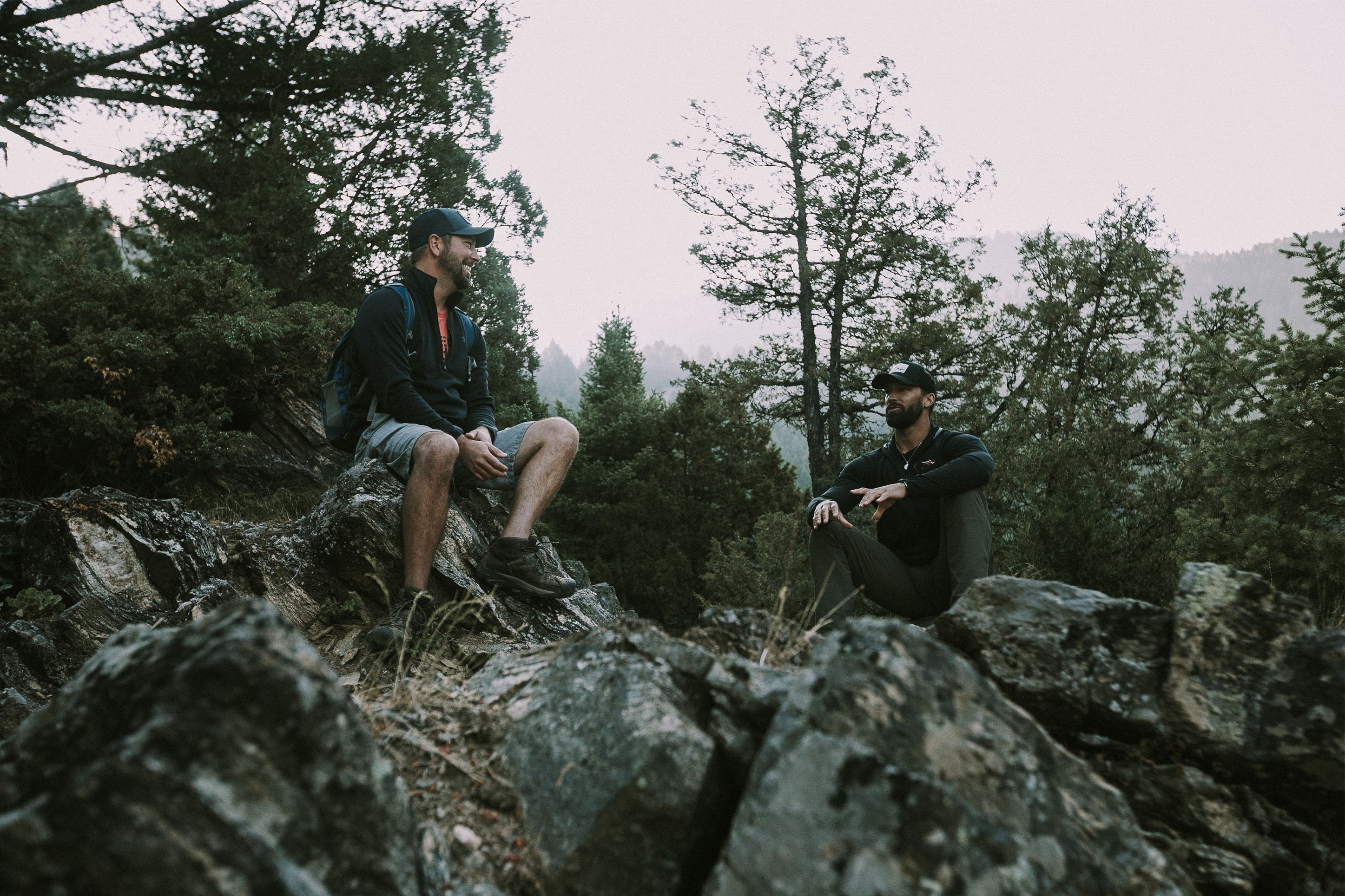 Two men sitting on a rock on a hike. 