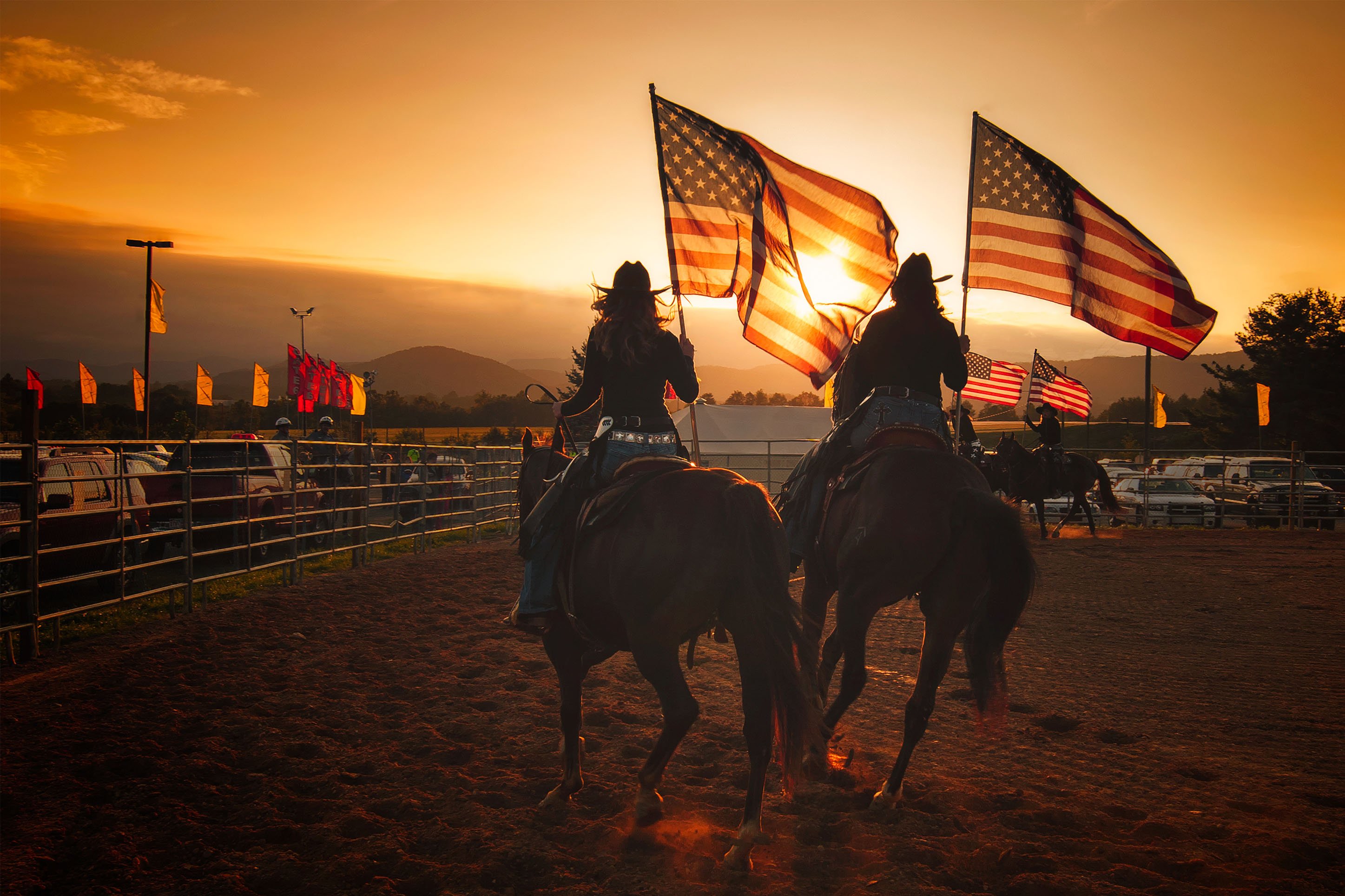 Two women carrying flags at the rodeo. 