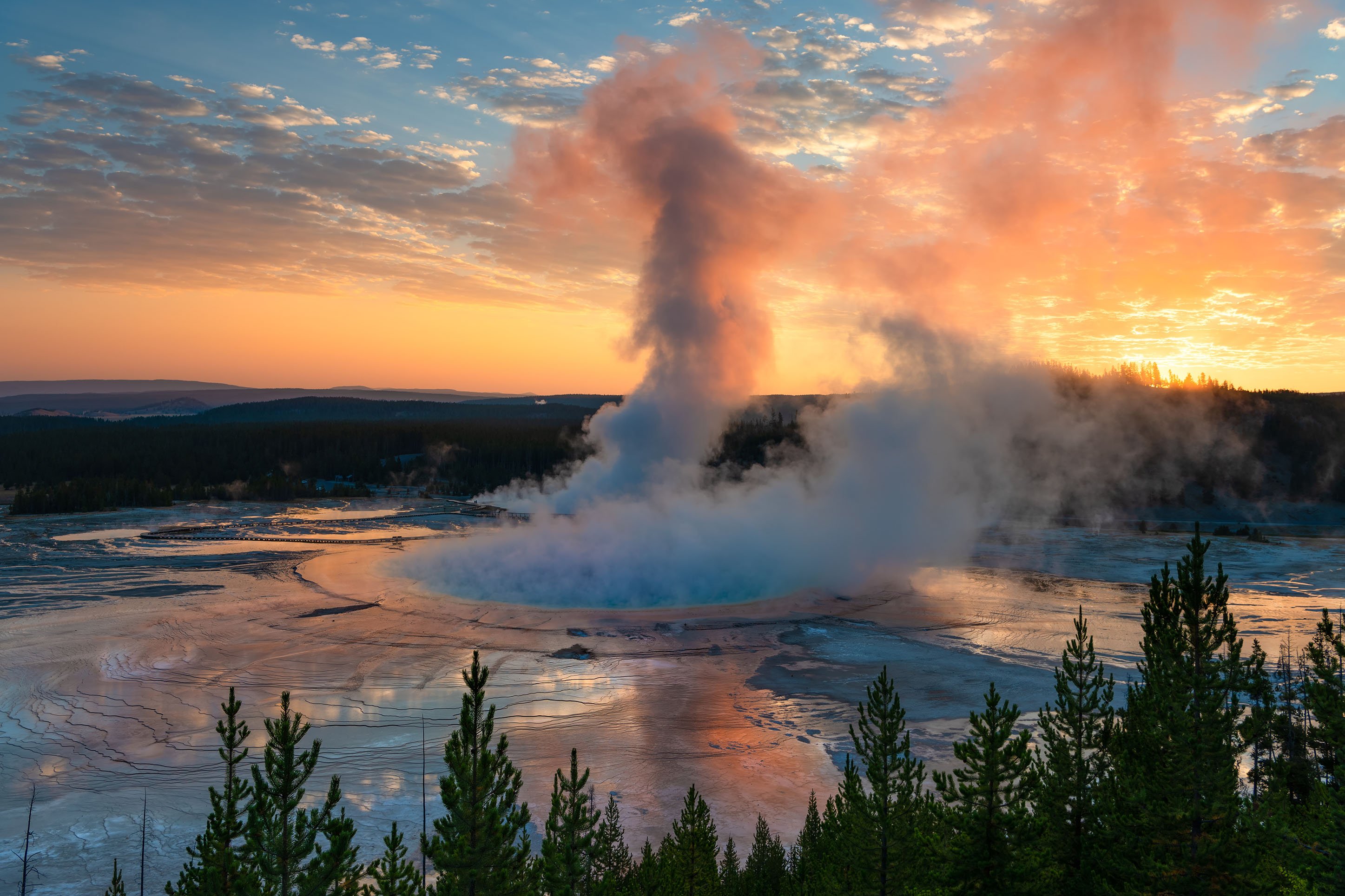 Colorful sunset with a geyser in Yellowstone National Park.