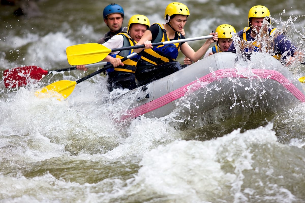 A raft of five people going whitewater rafting down the Madison River
