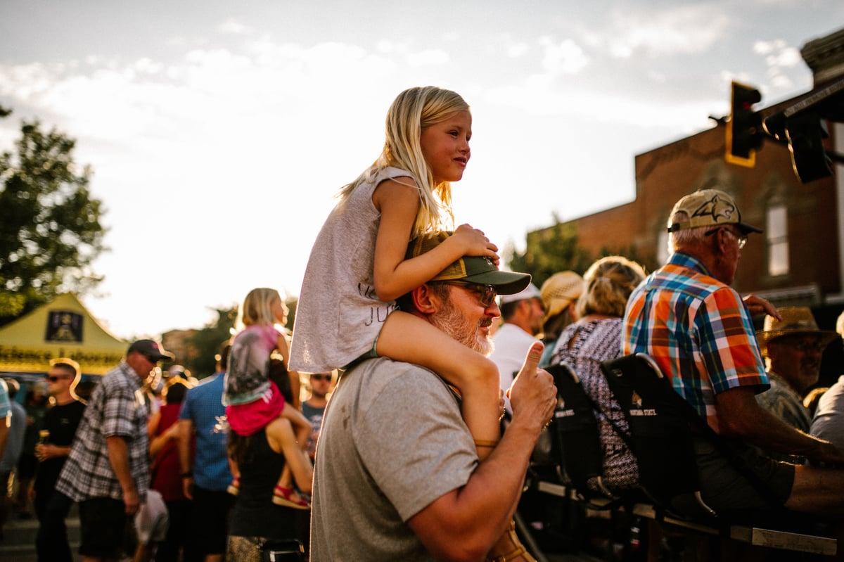 A girl sits on the shoulders of her dad while watching music at Music on Main in Bozeman