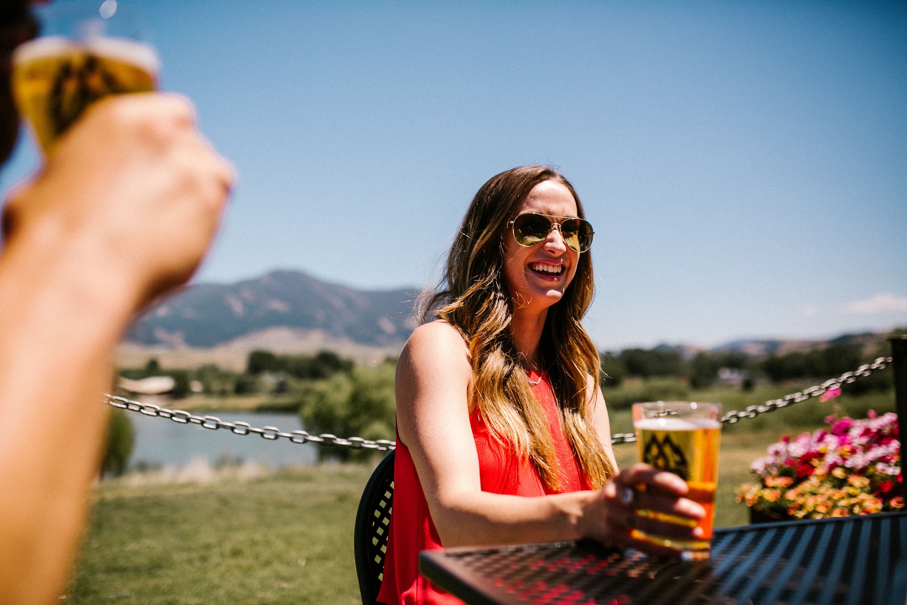 Photo of a woman smiling with a beer on the MAP Brewing patio