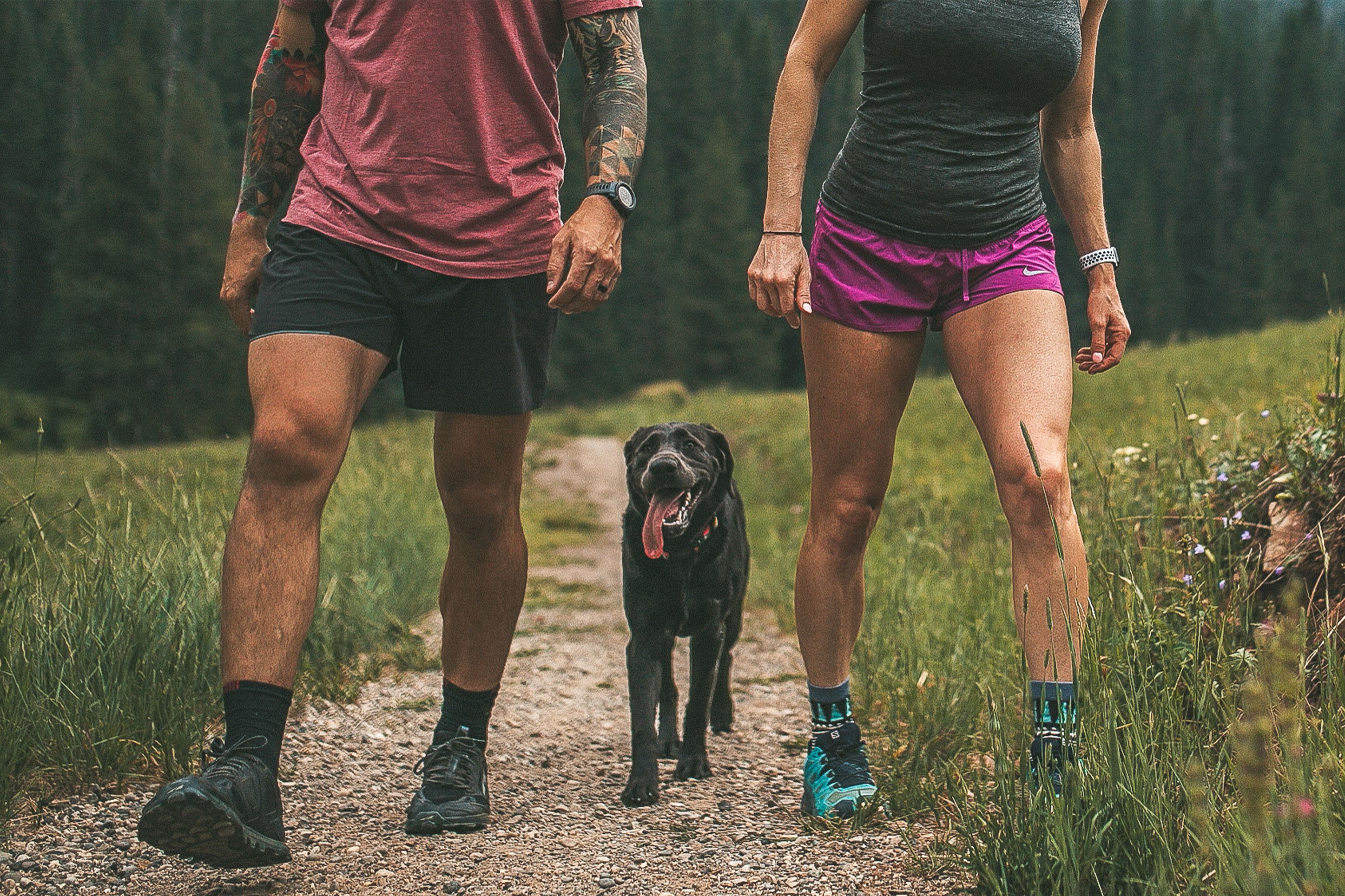 Man and woman hiking with a black dog