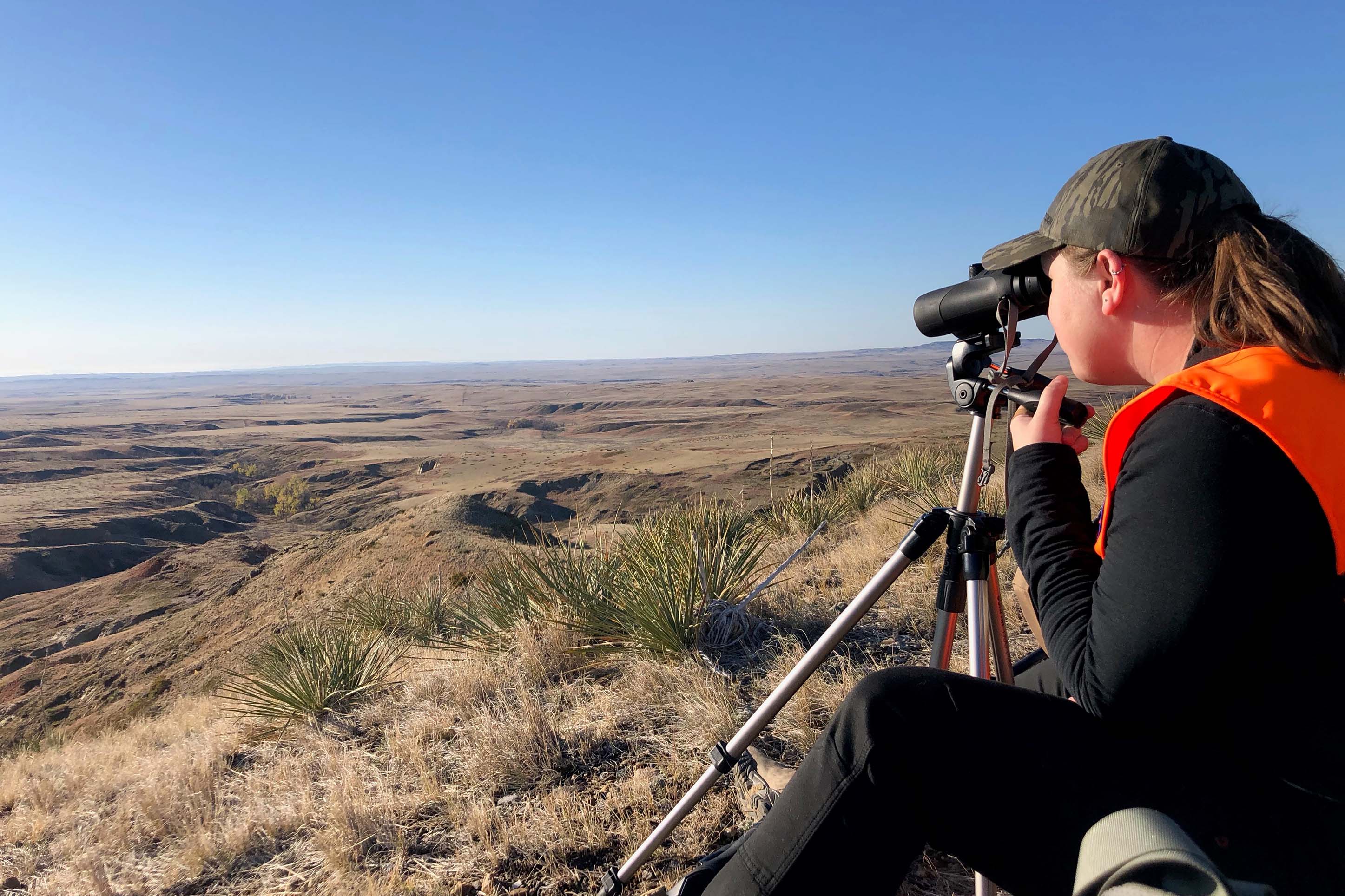 woman using binoculars to spot animals while hunting in Montana