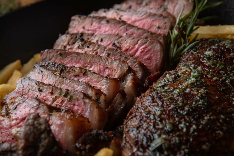 Image of steak filet, medium rare with rosemary garnish