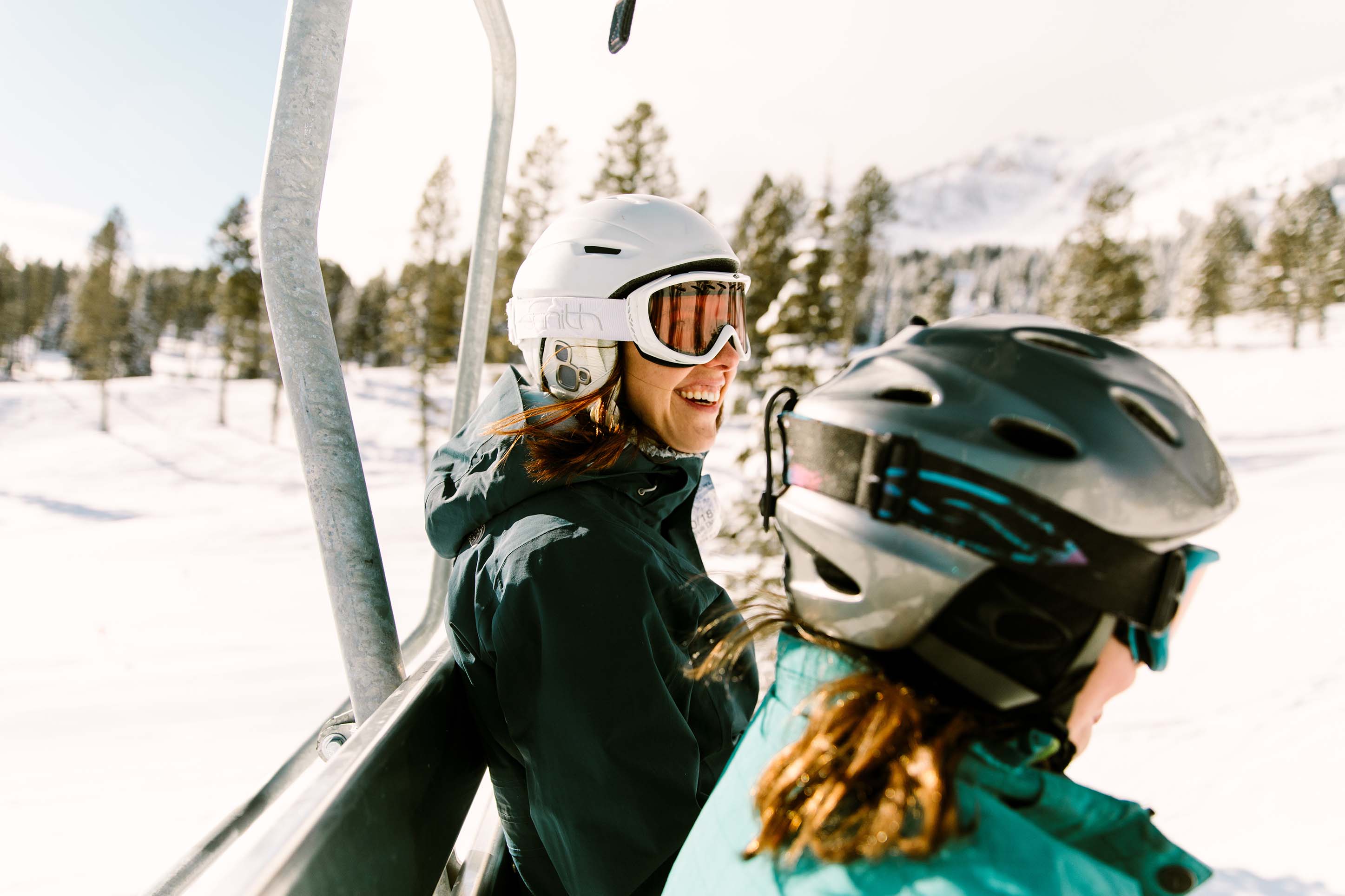 Two women smiling on a ski lift. 