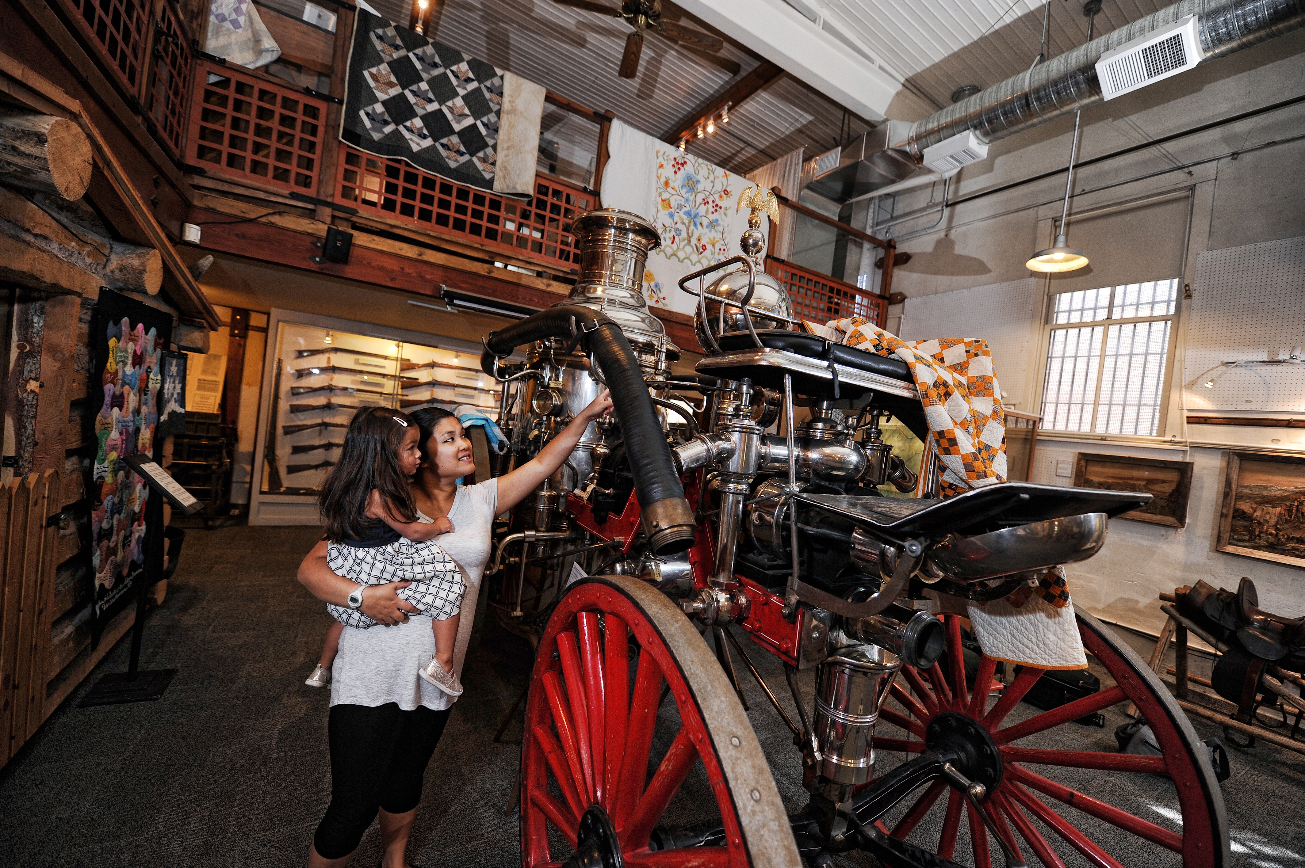 mother and daughter look at an old automobile in a museum