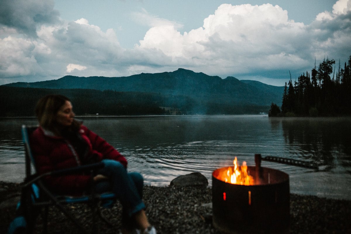 Woman sitting in front of a campfire at Hyalite Reservoir