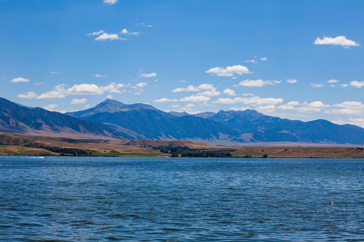 Ennis Lake in the summer, with calm, blue water and mountains in the background.