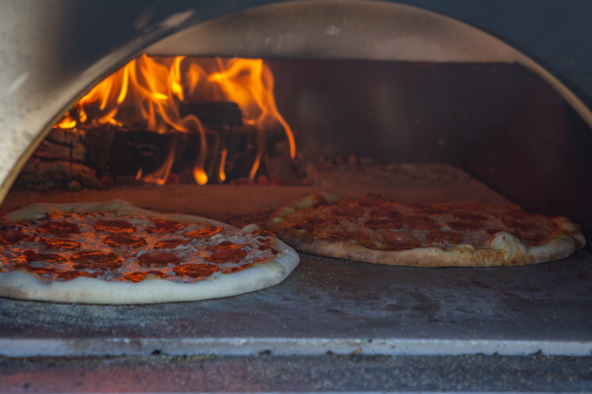 pizzas in a brick oven at the ugly onion pizza