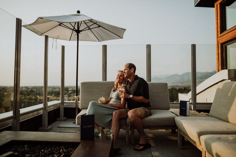 A couple sitting at Sky Shed's outdoor rooftop patio holding cocktails