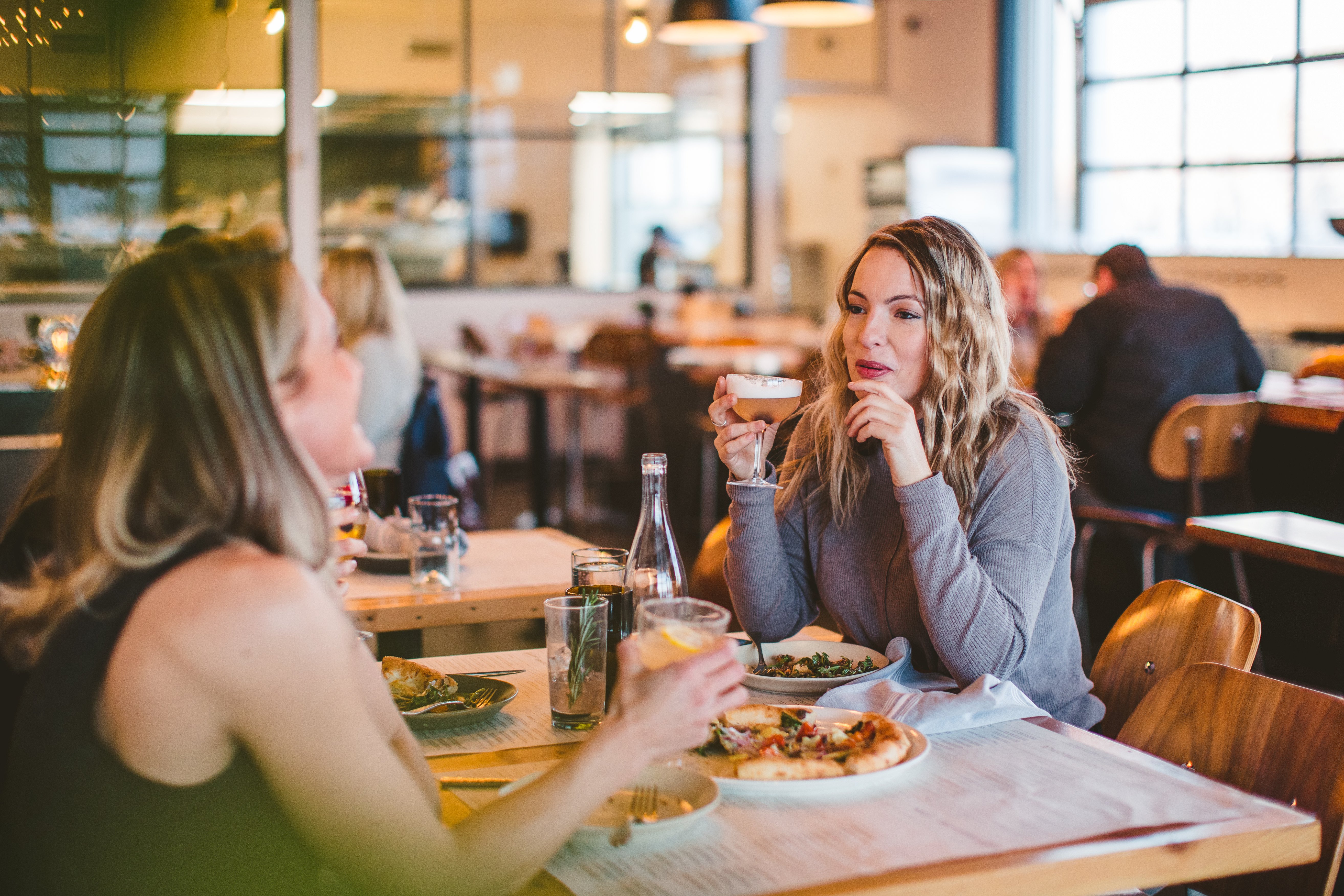 Two women drinking cocktails and eating pizza at Tanglewood Grill and Tap