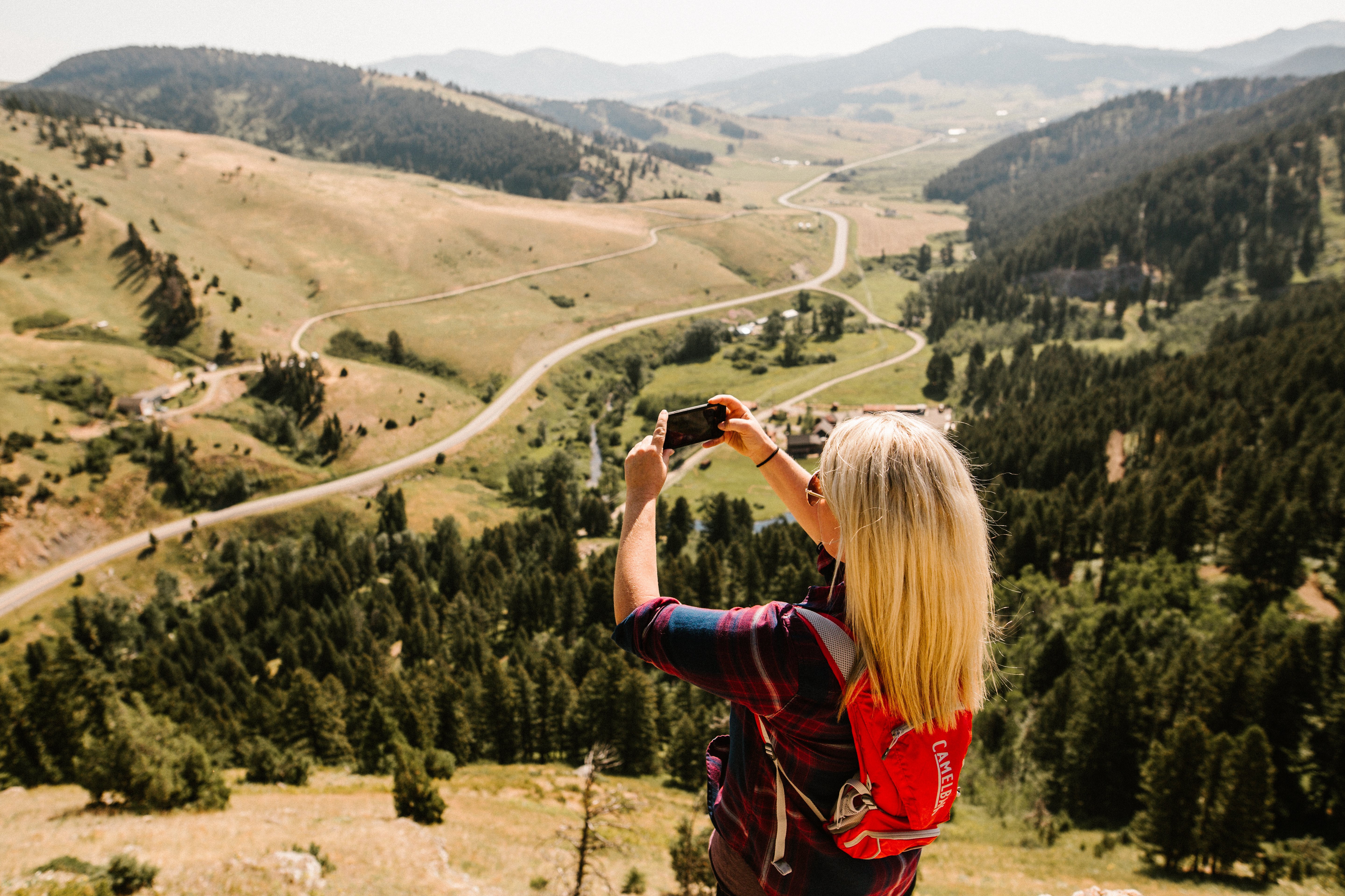 girl taking a photo of the view on top of the college M trail