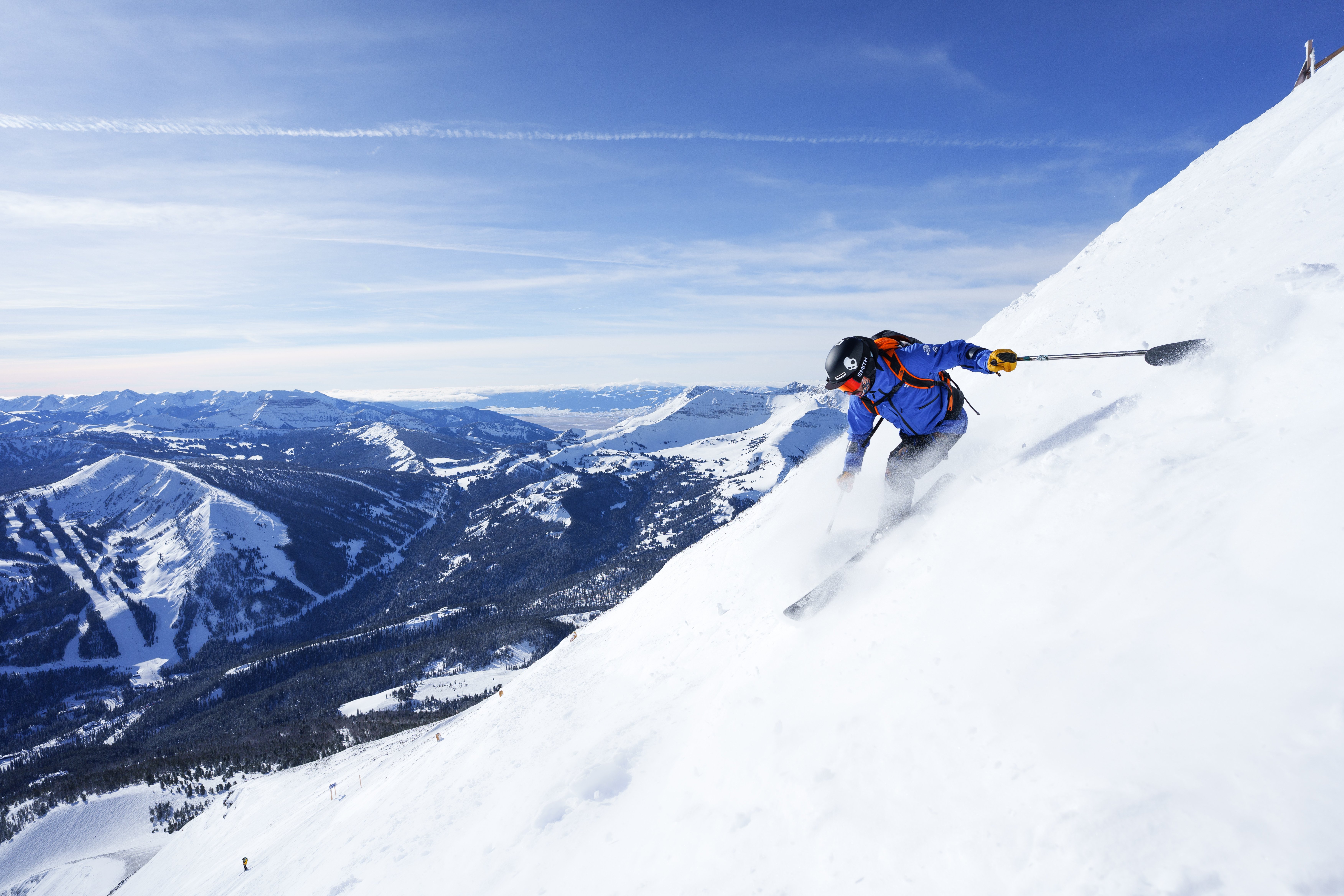 Man skiing down a steep run at Big Sky Resort with a view of the mountains in the background